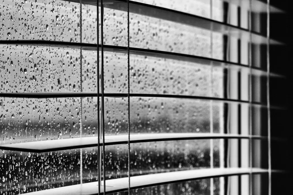 Vidro de janela com gotículas de chuva ao lado de fora