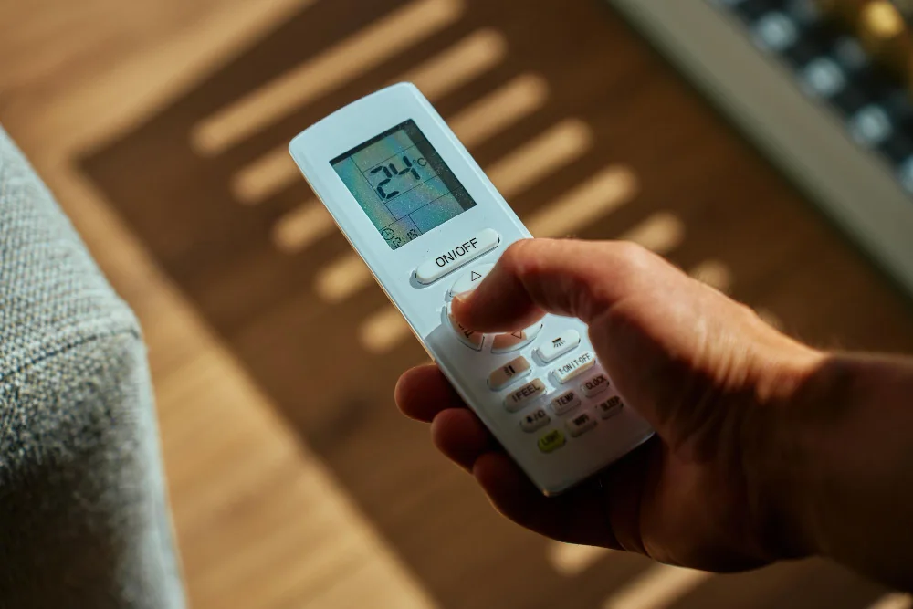 Mão segurando controle de ar-condicionado que não está gelando