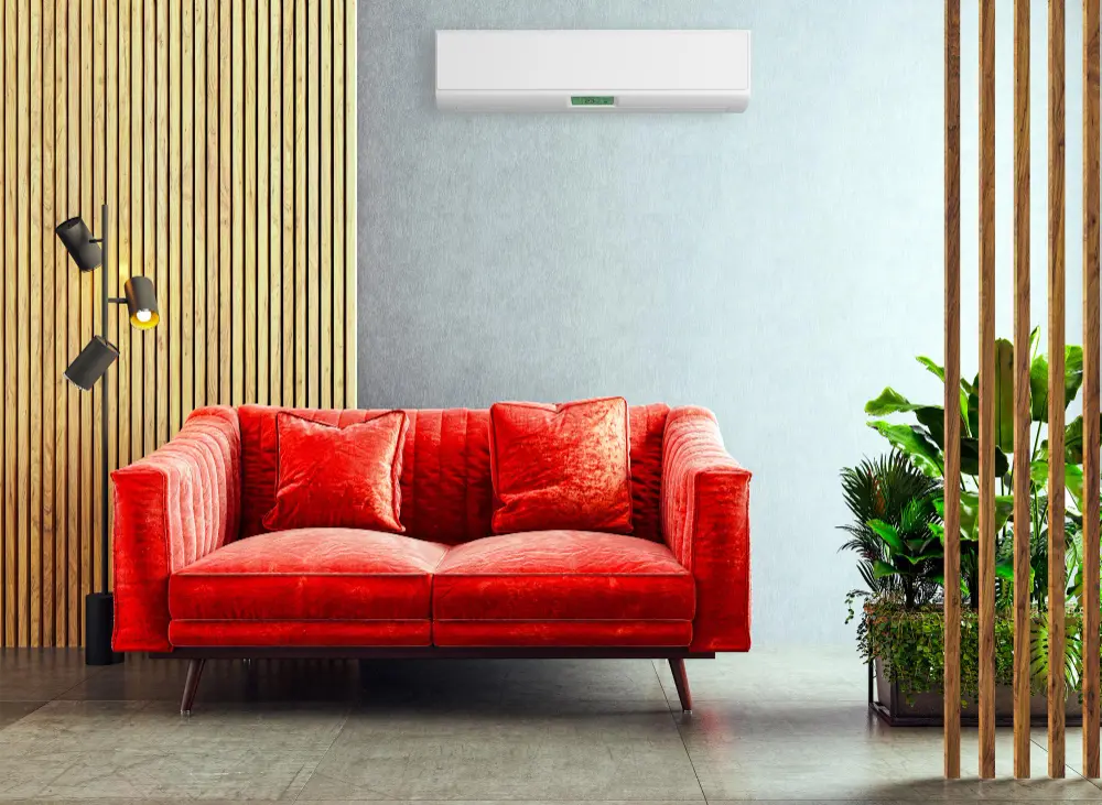 Sala de estar com sofá vermelho de dois lugares, plantas e luminária com ar condicionado split em parede ao fundo 